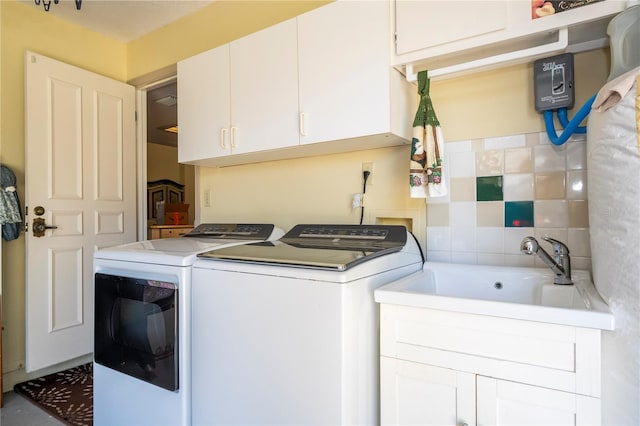 clothes washing area featuring washing machine and dryer, sink, and cabinets