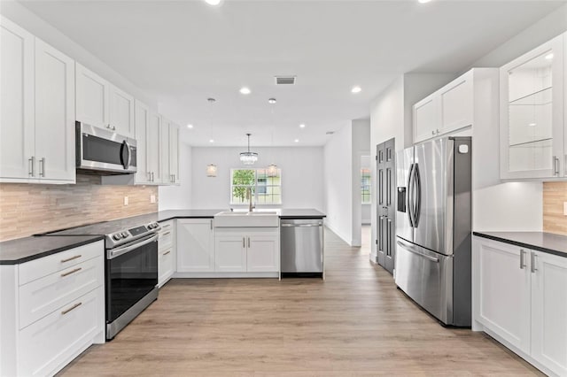 kitchen with kitchen peninsula, white cabinetry, pendant lighting, and appliances with stainless steel finishes