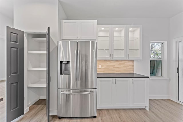 kitchen with light hardwood / wood-style floors, decorative backsplash, stainless steel fridge, and white cabinetry