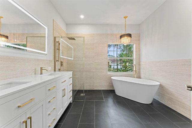 bathroom with an inviting chandelier, tile patterned flooring, separate shower and tub, vanity, and tile walls