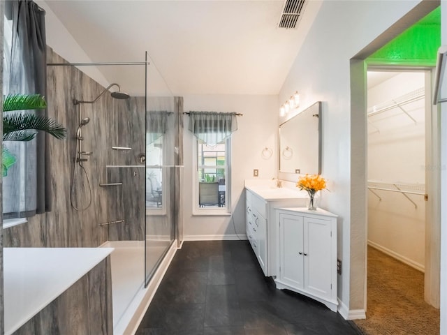 bathroom with a tile shower, vanity, and lofted ceiling