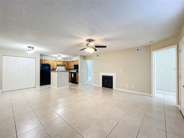 unfurnished living room featuring ceiling fan, light tile patterned flooring, and a textured ceiling