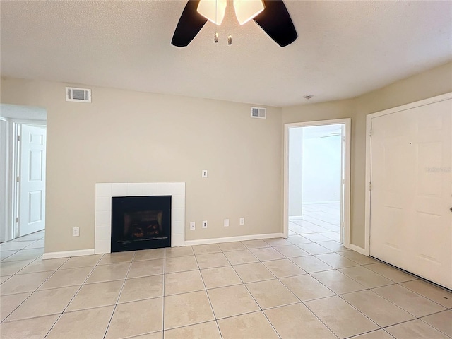 unfurnished living room with a tile fireplace, light tile patterned floors, a textured ceiling, and ceiling fan