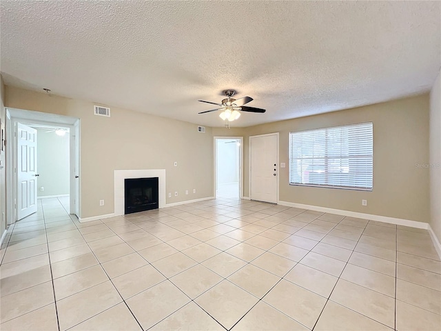 unfurnished living room featuring ceiling fan, light tile patterned flooring, and a textured ceiling