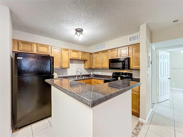 kitchen with a textured ceiling, sink, black appliances, light tile patterned floors, and a center island