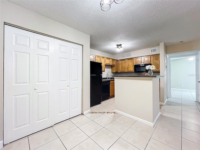 kitchen with a textured ceiling, sink, black appliances, light tile patterned floors, and a kitchen island