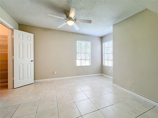 spare room featuring ceiling fan, light tile patterned flooring, and a textured ceiling