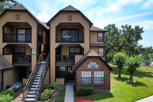 townhome / multi-family property featuring brick siding, stairway, and a front yard