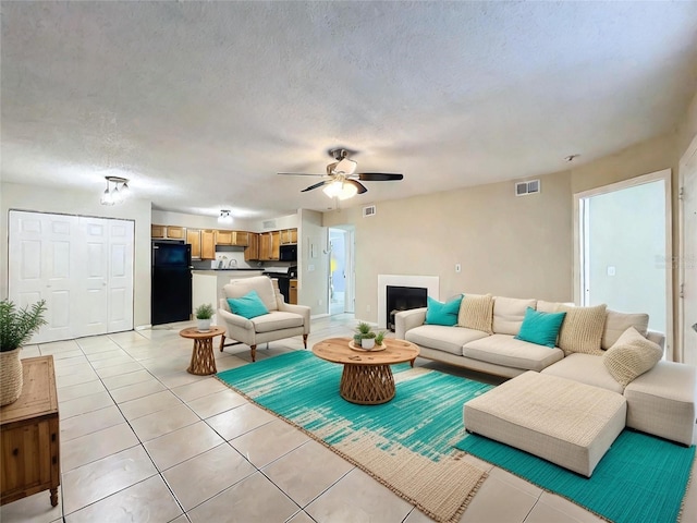 living room featuring visible vents, a fireplace, a textured ceiling, and light tile patterned flooring