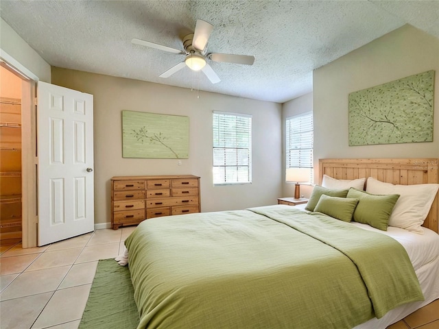 bedroom with a ceiling fan, a textured ceiling, and light tile patterned floors