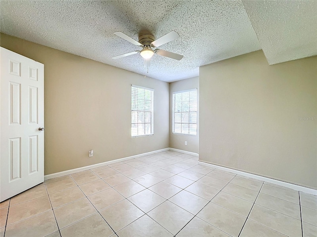 unfurnished room with a ceiling fan, a textured ceiling, baseboards, and light tile patterned floors