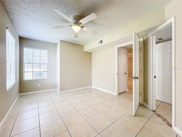 spare room featuring a ceiling fan, visible vents, a textured ceiling, and light tile patterned floors