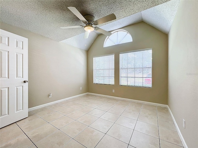 unfurnished room featuring ceiling fan, a textured ceiling, light tile patterned flooring, baseboards, and vaulted ceiling