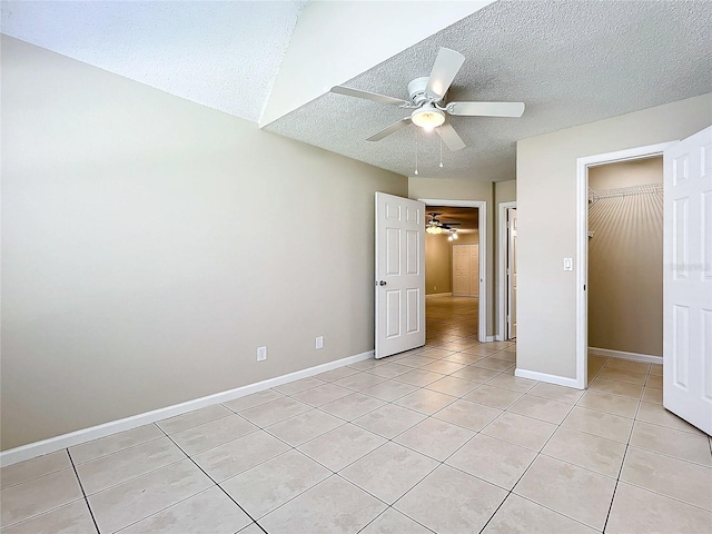 unfurnished bedroom with light tile patterned floors, baseboards, ceiling fan, a textured ceiling, and a closet