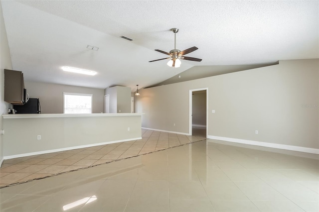 spare room with ceiling fan, lofted ceiling, a textured ceiling, and light tile patterned floors