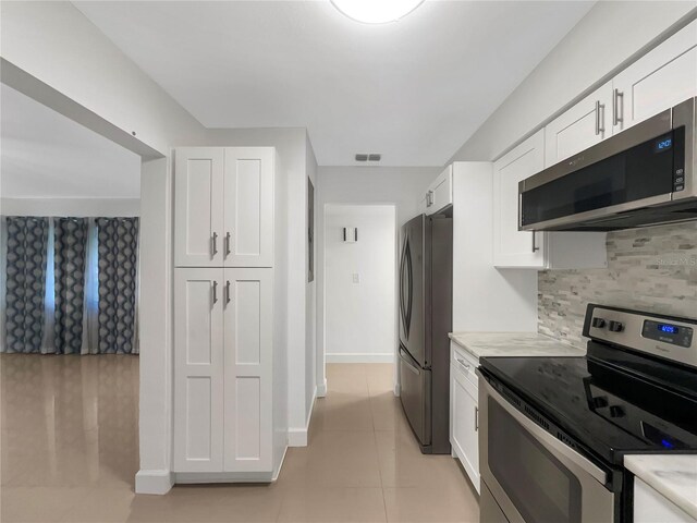 kitchen featuring white cabinets, light tile patterned floors, stainless steel appliances, and tasteful backsplash