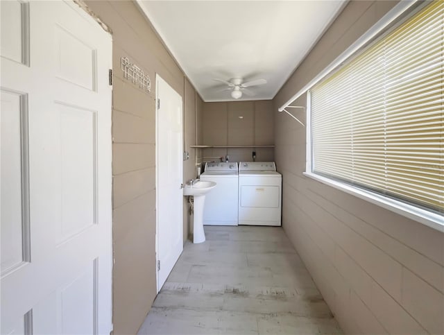 clothes washing area featuring washing machine and dryer, ceiling fan, sink, and light hardwood / wood-style floors