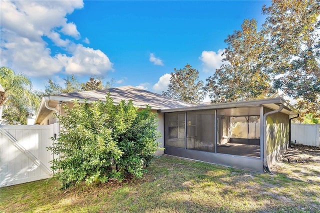 back of property with a sunroom and a yard