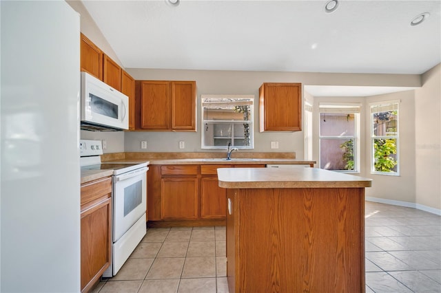 kitchen with light tile patterned floors, white appliances, a center island, and sink