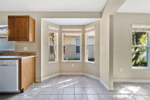 kitchen featuring light tile patterned flooring, white dishwasher, and a healthy amount of sunlight