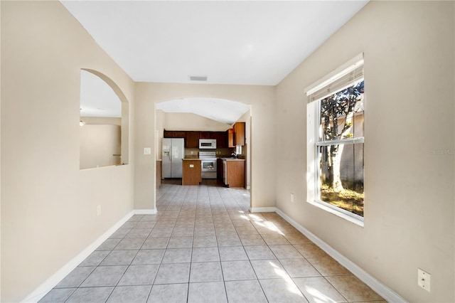 corridor featuring light tile patterned floors and vaulted ceiling