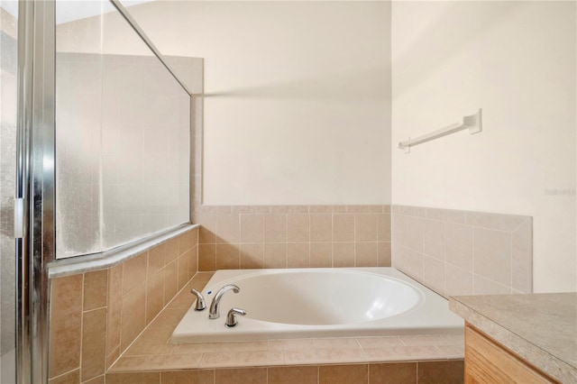 bathroom featuring tiled tub and vanity