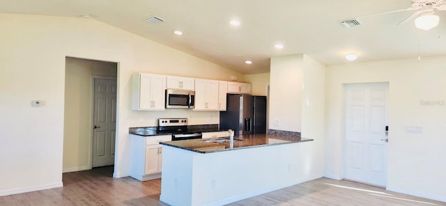 kitchen featuring white cabinets, appliances with stainless steel finishes, kitchen peninsula, and vaulted ceiling