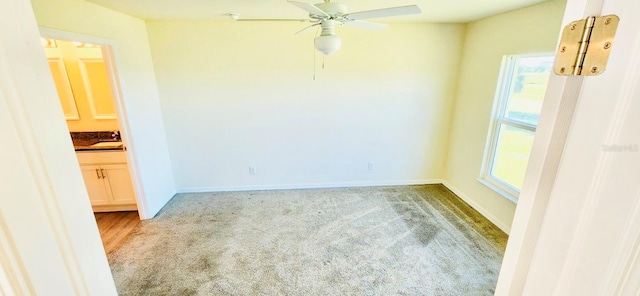 carpeted spare room featuring ceiling fan and sink