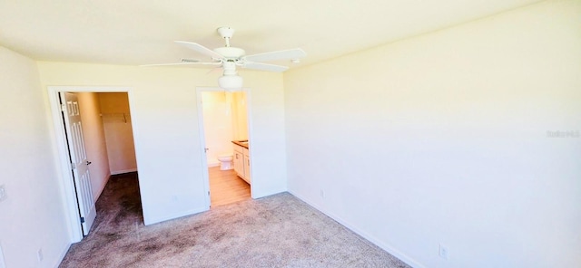 unfurnished bedroom featuring ceiling fan, a walk in closet, light carpet, and a closet