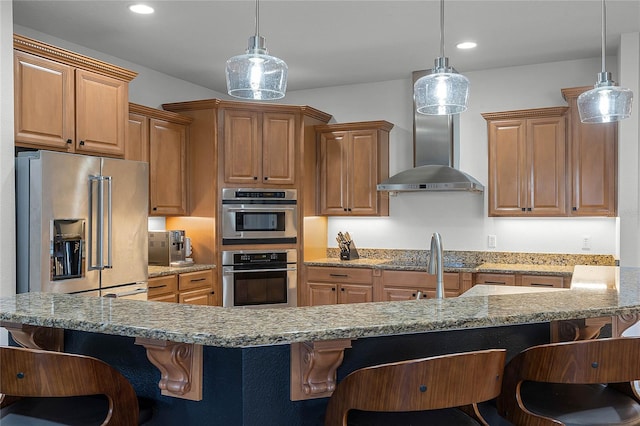 kitchen with appliances with stainless steel finishes, hanging light fixtures, and a breakfast bar area