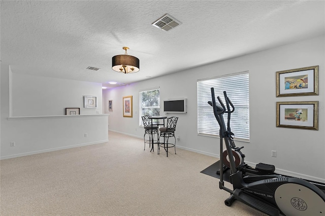 workout area featuring a textured ceiling and light carpet