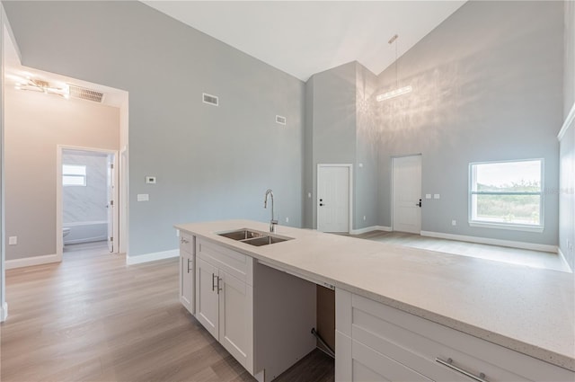 kitchen featuring white cabinetry, sink, pendant lighting, lofted ceiling, and light wood-type flooring