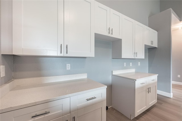 kitchen featuring light stone counters, white cabinets, and light wood-type flooring