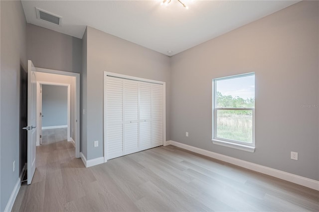 unfurnished bedroom with light wood-type flooring and a closet