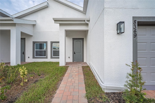 doorway to property with a garage and a lawn