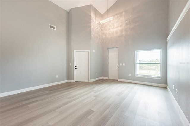 empty room featuring high vaulted ceiling and light wood-type flooring