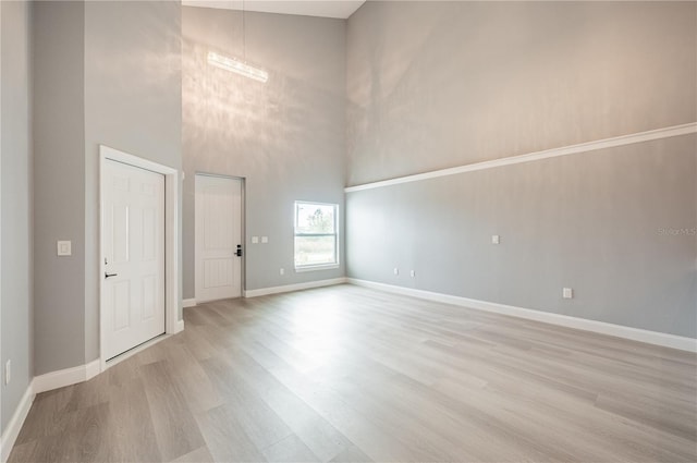 spare room with light hardwood / wood-style floors and a high ceiling