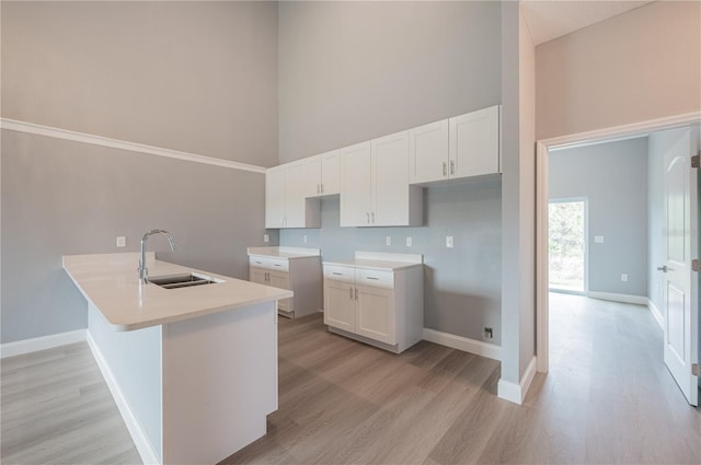 kitchen with light wood-type flooring, white cabinetry, and sink