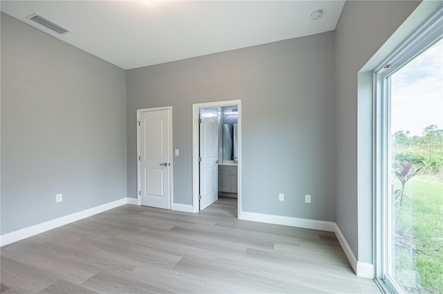 unfurnished bedroom featuring light hardwood / wood-style floors and ensuite bath