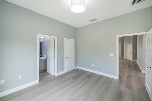 unfurnished bedroom featuring connected bathroom and light hardwood / wood-style flooring