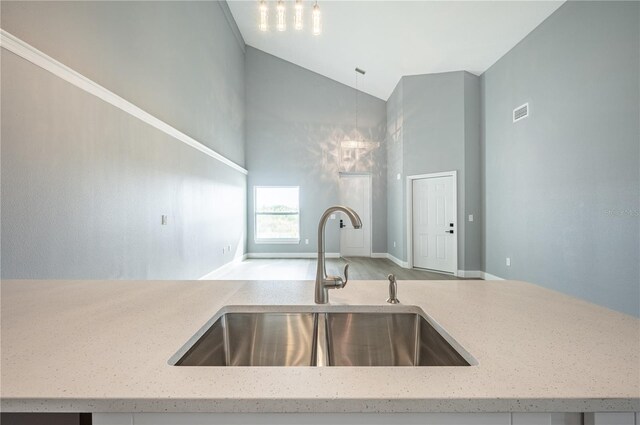 kitchen with light stone countertops, decorative light fixtures, vaulted ceiling, and sink