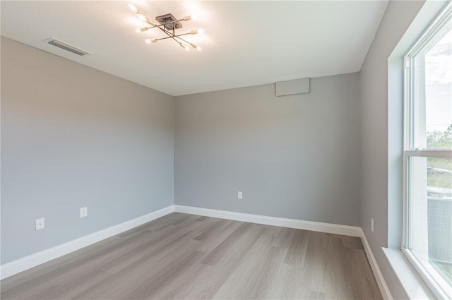 empty room with light hardwood / wood-style flooring and a chandelier