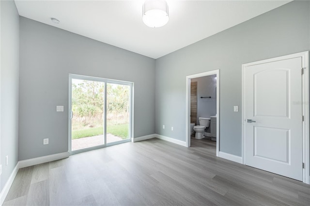 unfurnished bedroom featuring connected bathroom, light hardwood / wood-style floors, and access to exterior