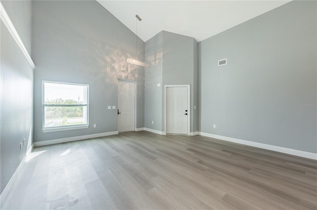 spare room featuring light wood-type flooring and high vaulted ceiling