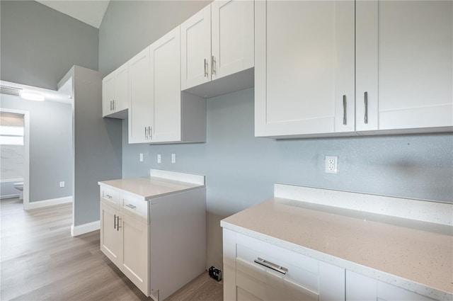 kitchen featuring white cabinets, light hardwood / wood-style flooring, and light stone counters