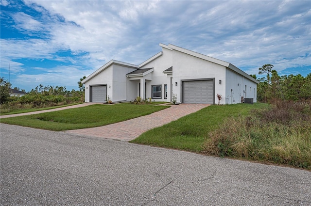 view of front of property featuring central air condition unit, a front lawn, and a garage