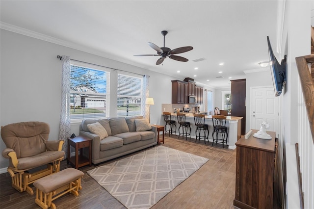 living room with ceiling fan, crown molding, and light hardwood / wood-style flooring