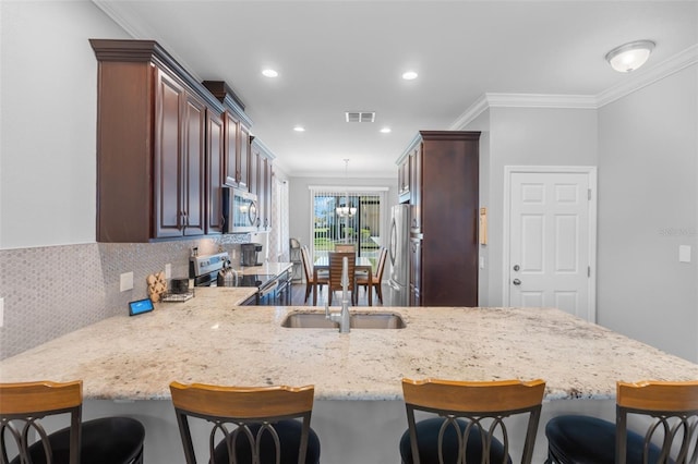 kitchen with stainless steel appliances, backsplash, kitchen peninsula, crown molding, and pendant lighting