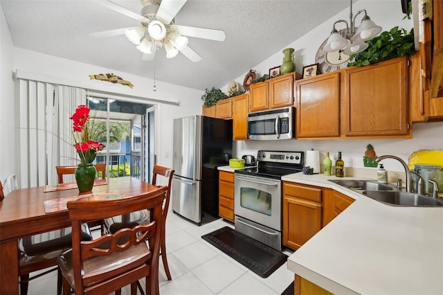 kitchen with sink, vaulted ceiling, ceiling fan, a textured ceiling, and appliances with stainless steel finishes