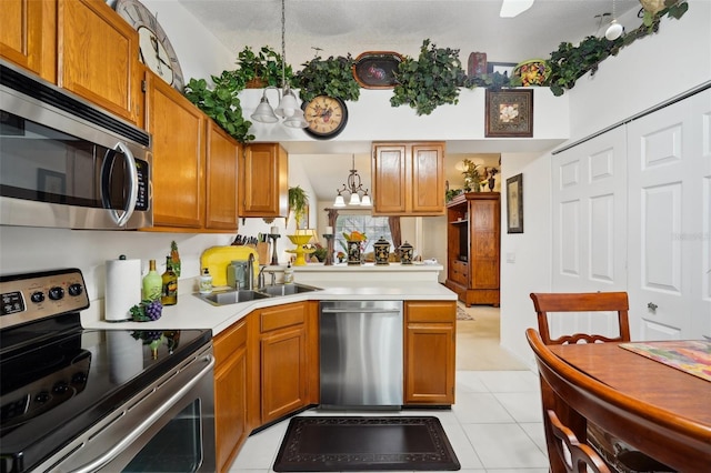 kitchen with pendant lighting, sink, light tile patterned floors, appliances with stainless steel finishes, and a chandelier